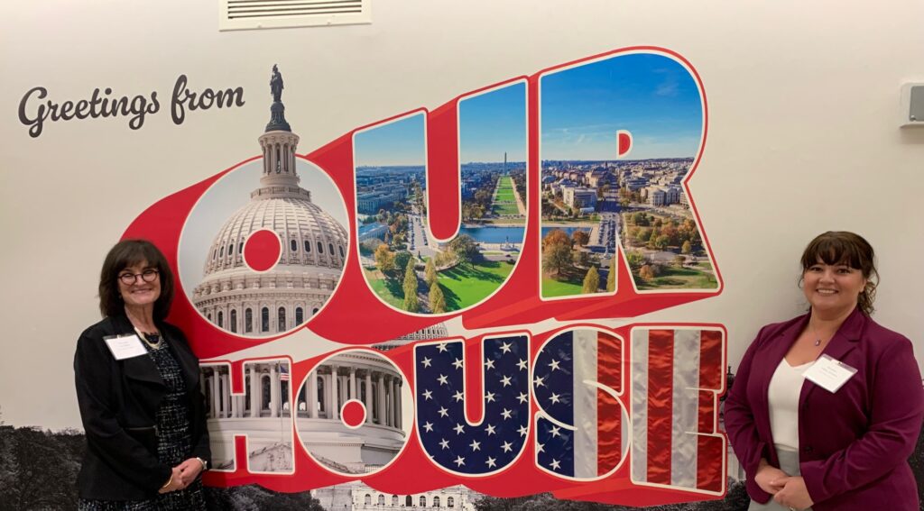 Helena Karchere standing in front of a "Greetings from Our House" mural in Washington D.C.