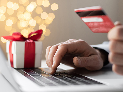 Person holding credit card with gift box and laptop keyboard