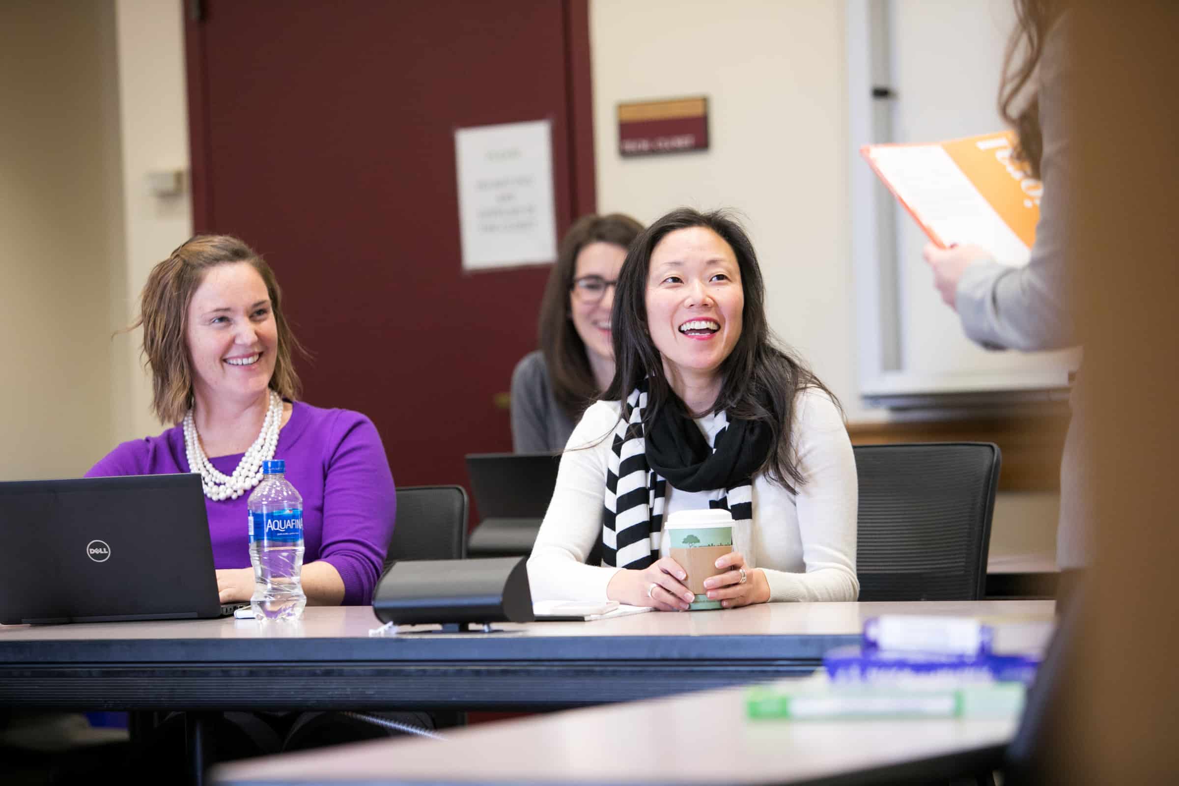 Students smiling and participating in discussion during a Daniels College classroom session.