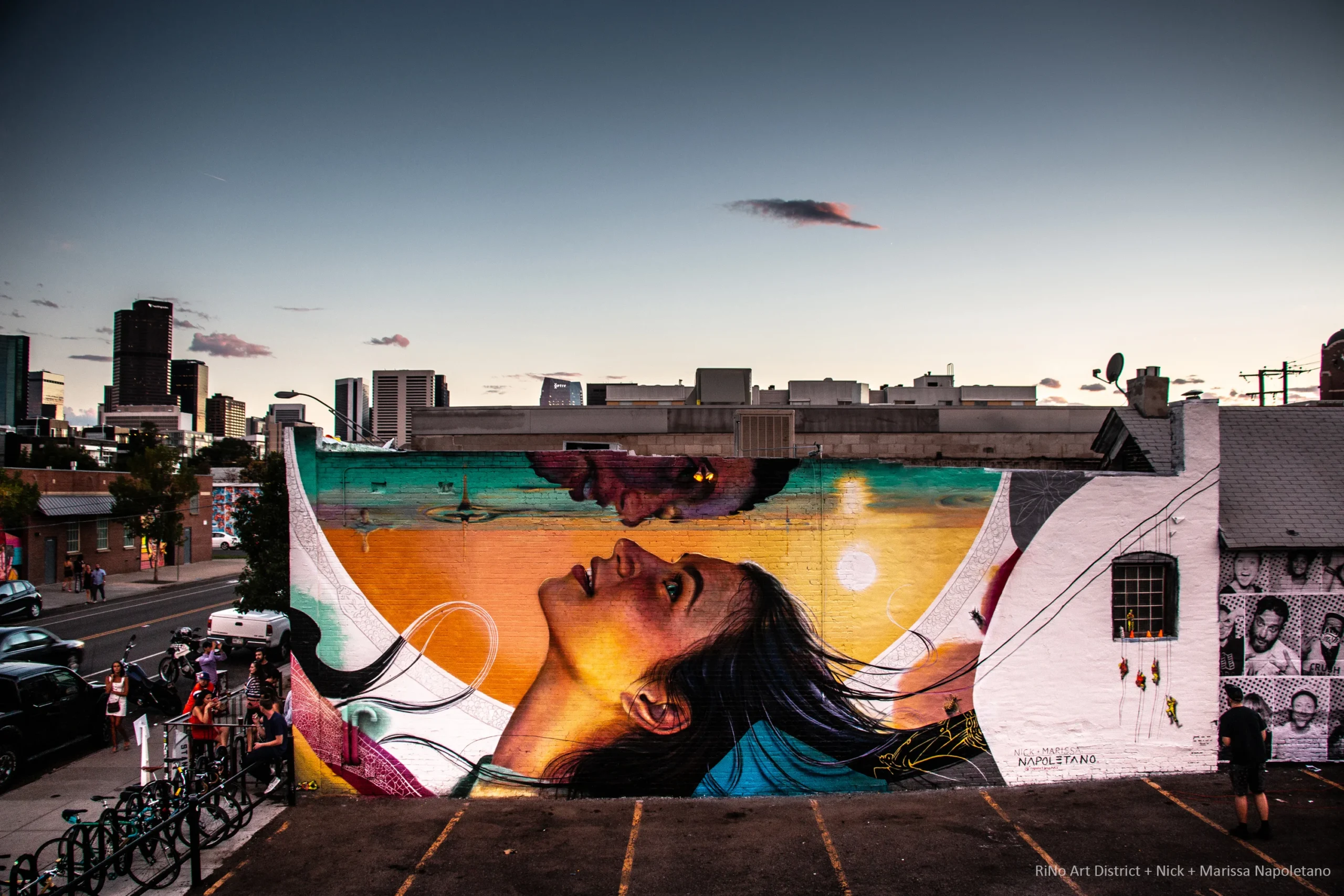 A mural on a brick wall of a building showing a woman looking up at the sky