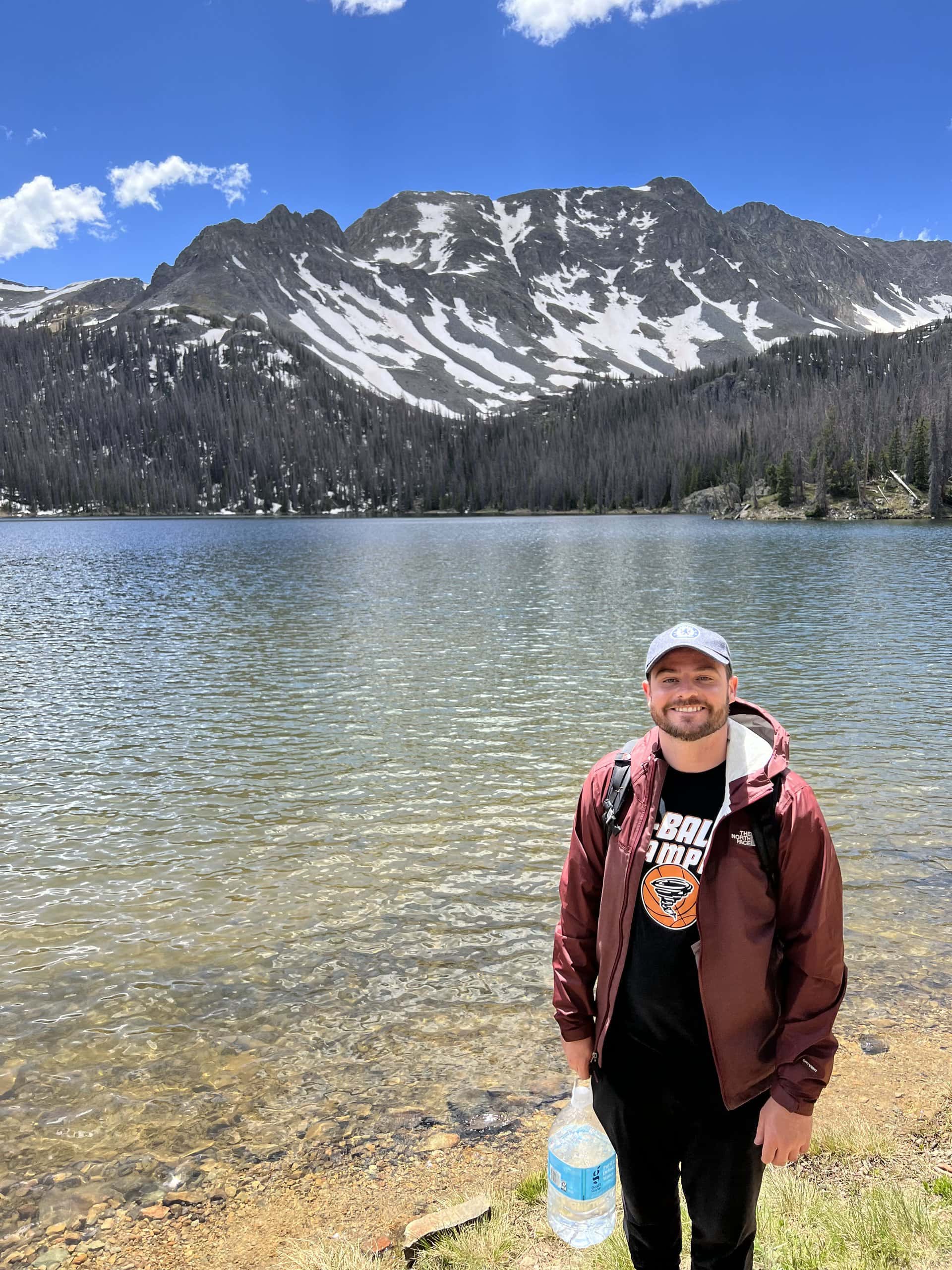 Chris Lee standing in front of a mountain lake