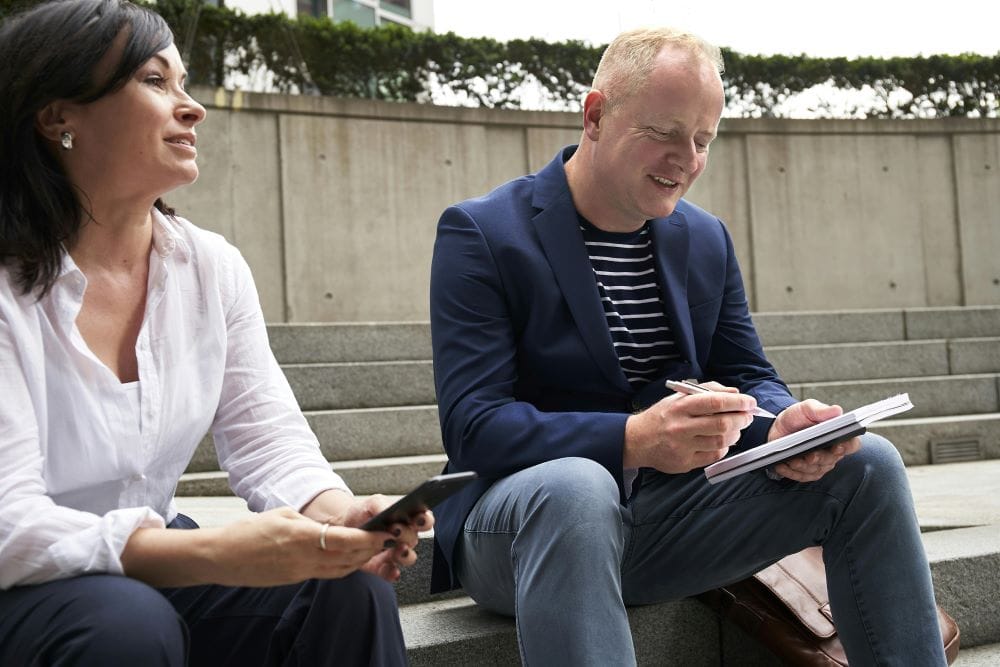 Man and woman going over notes outside on steps