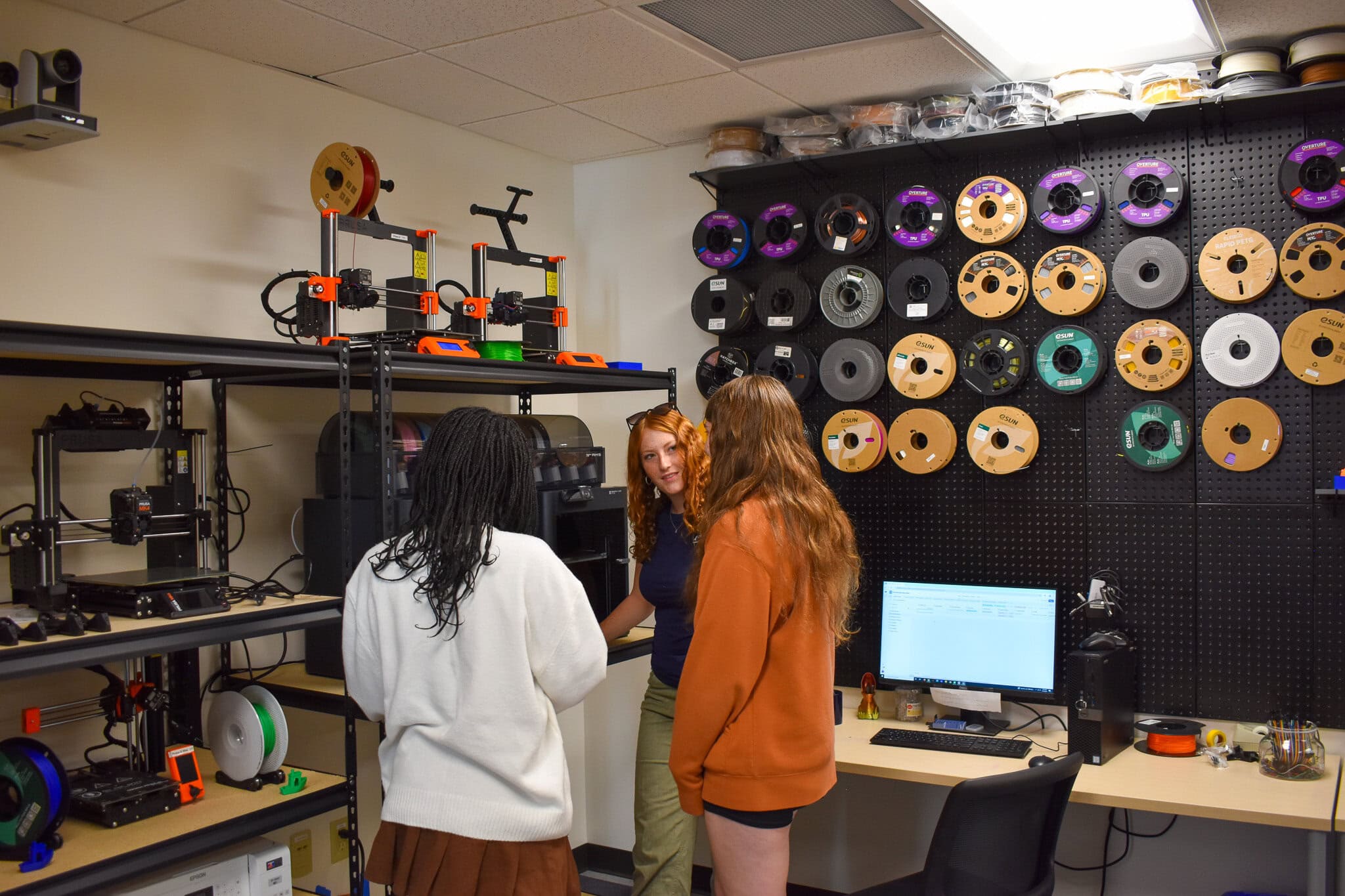 Students in front of spools of 3D printing materials and machines