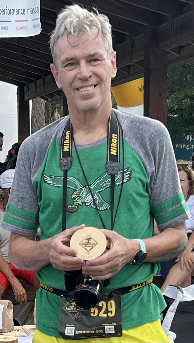 Larry Tomsic holding a running medal