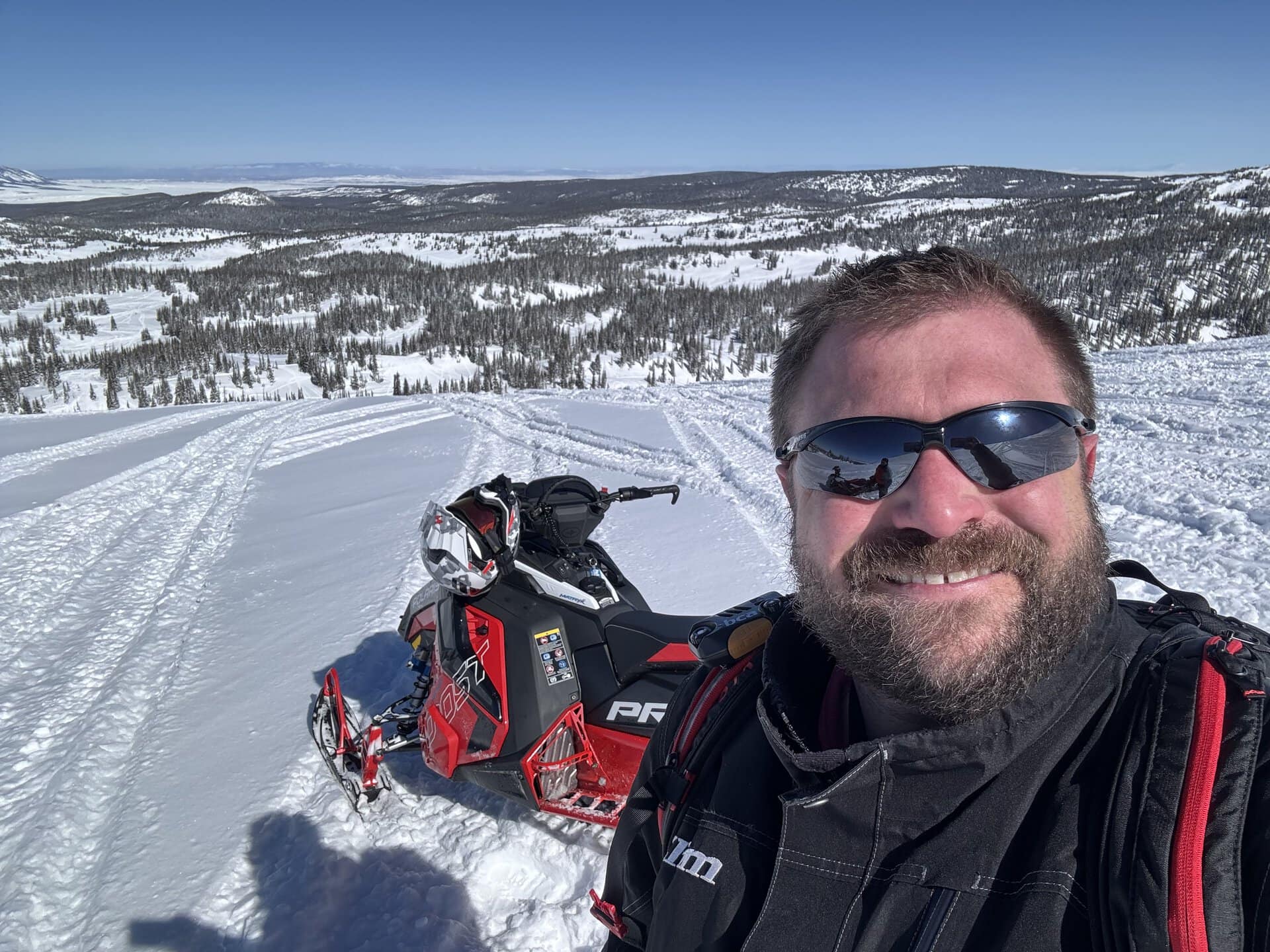 Marc Bastnagel selfie in front of a snowmobile and snowy landscape