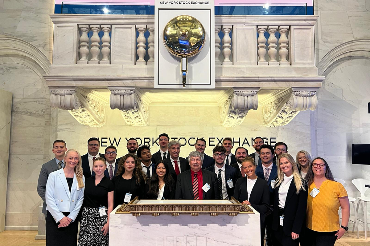 Dean Naomi Boyd and students posing in front of the New York Stock Exchange.
