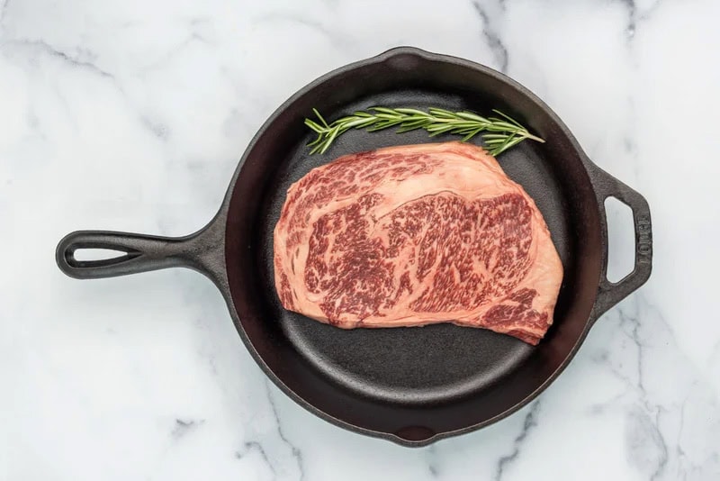 A ribeye steak in a cast iron skillet.