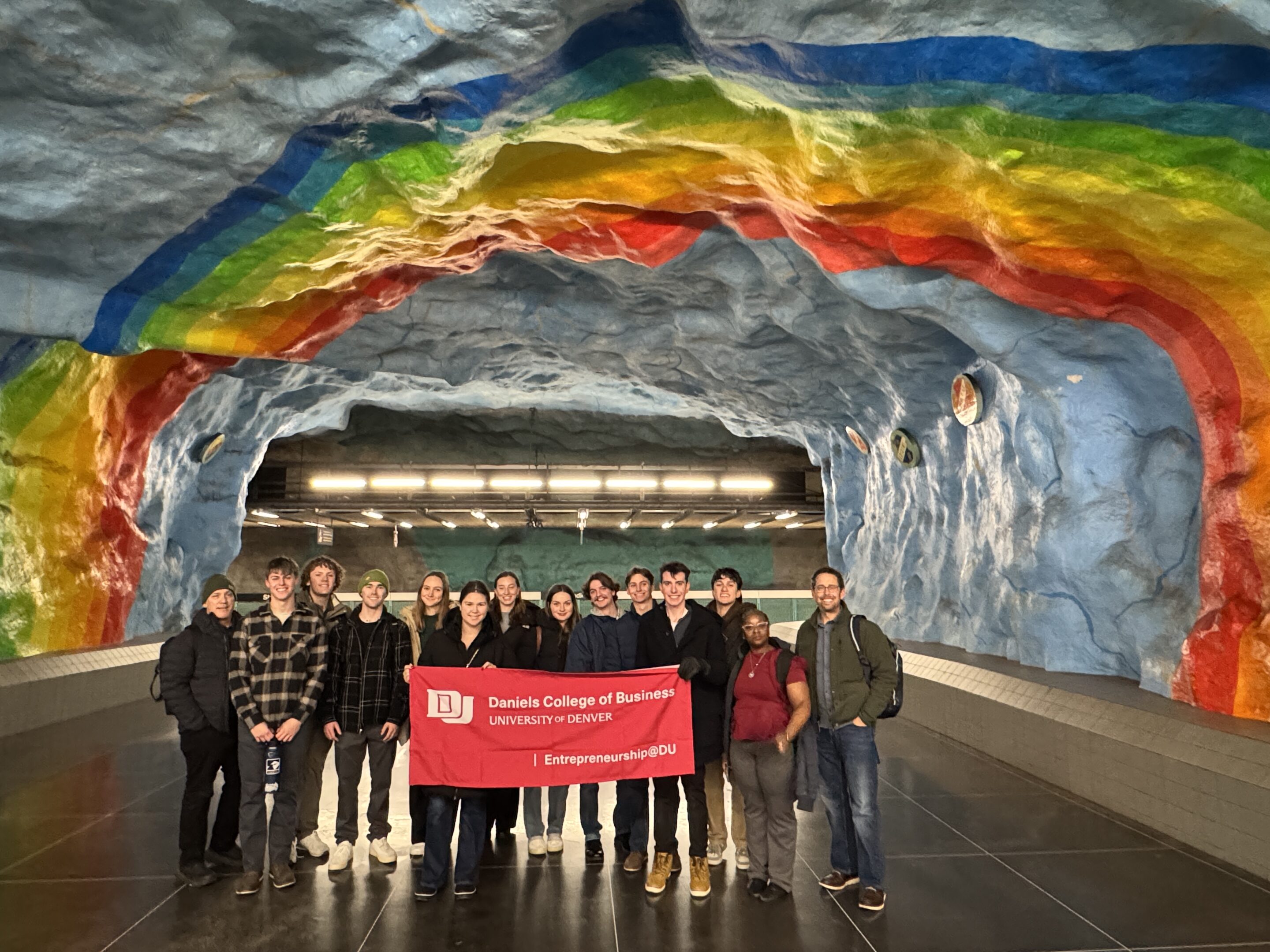 Students posing with a Daniels flag in a subway station