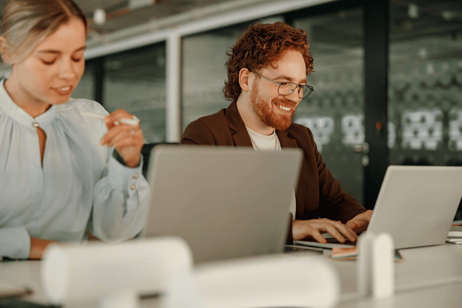 Young professionals smiling while working on laptops