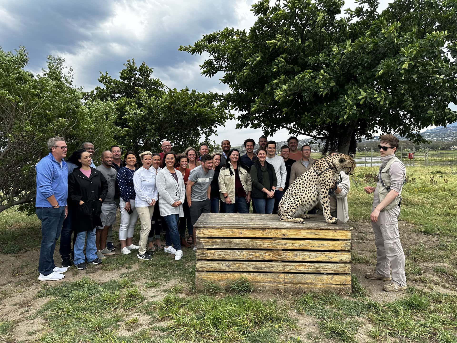 A group of students poses for a photo behind a cheetah