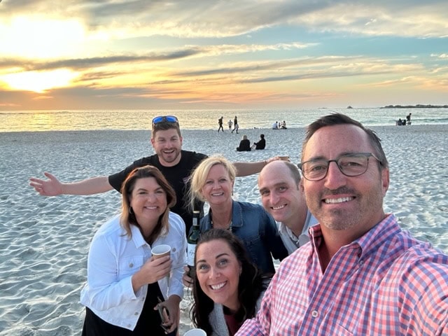 EMBA students pose for a selfie on the beach at sunset