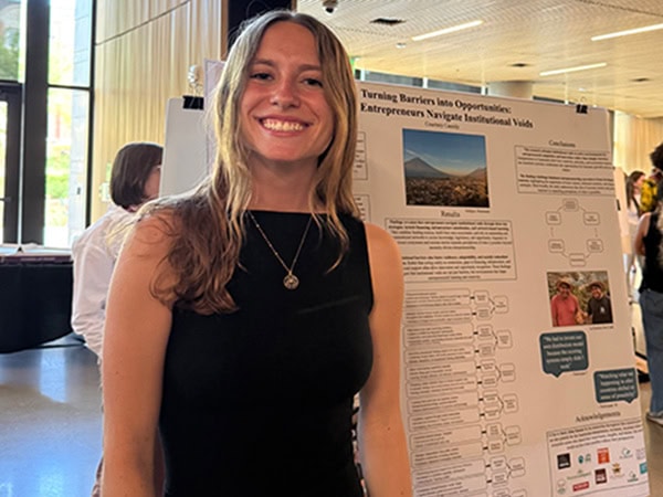 Student standing next to a research posterboard